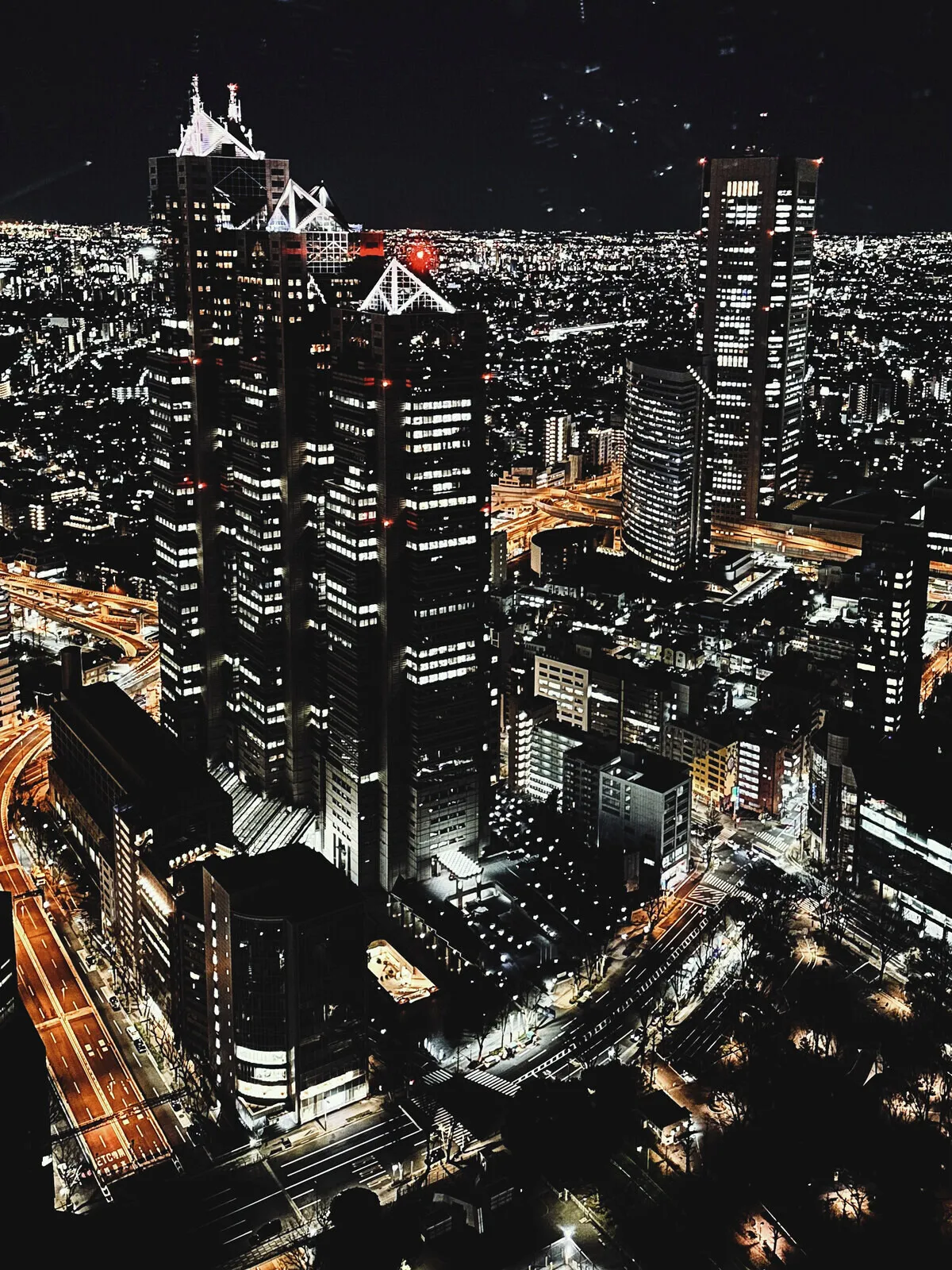 Tokyo at night from above, towers and lit streets.