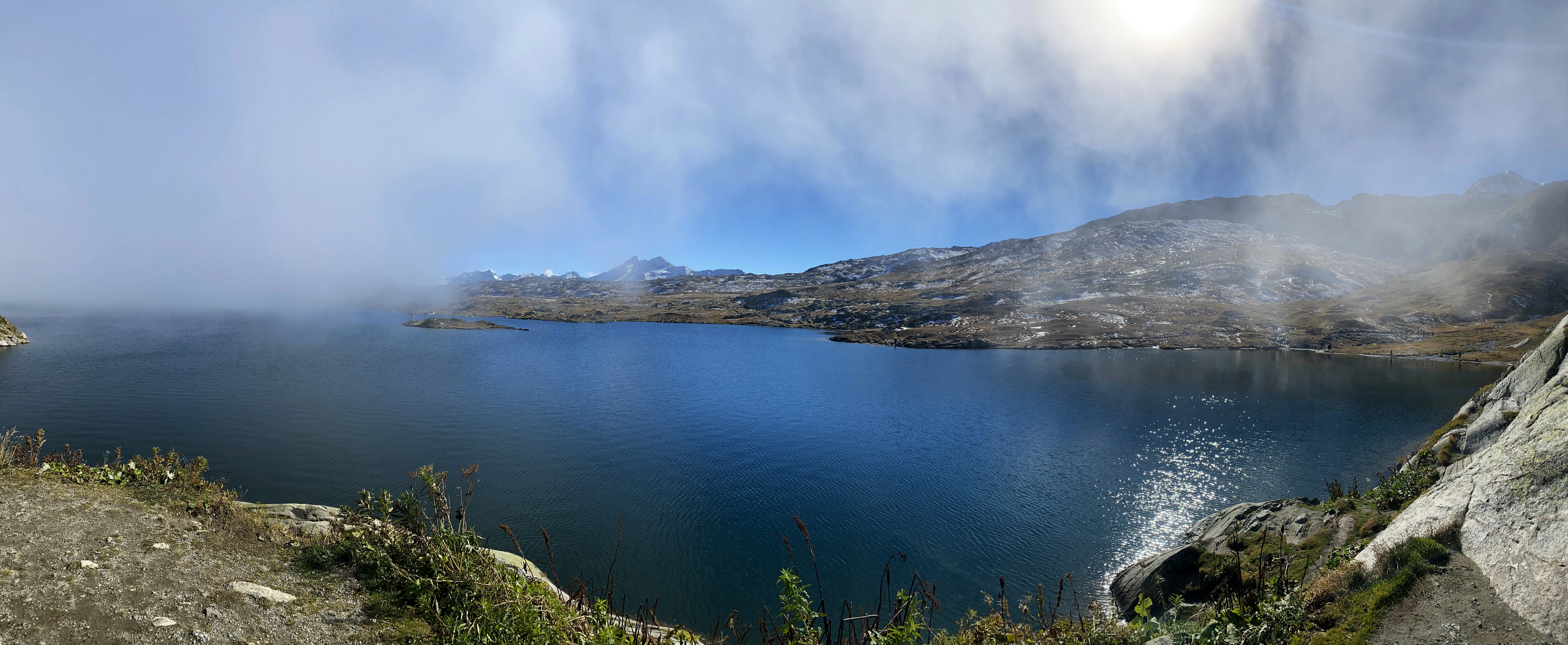 A high alpine lake with cloud coming down over the far shore.