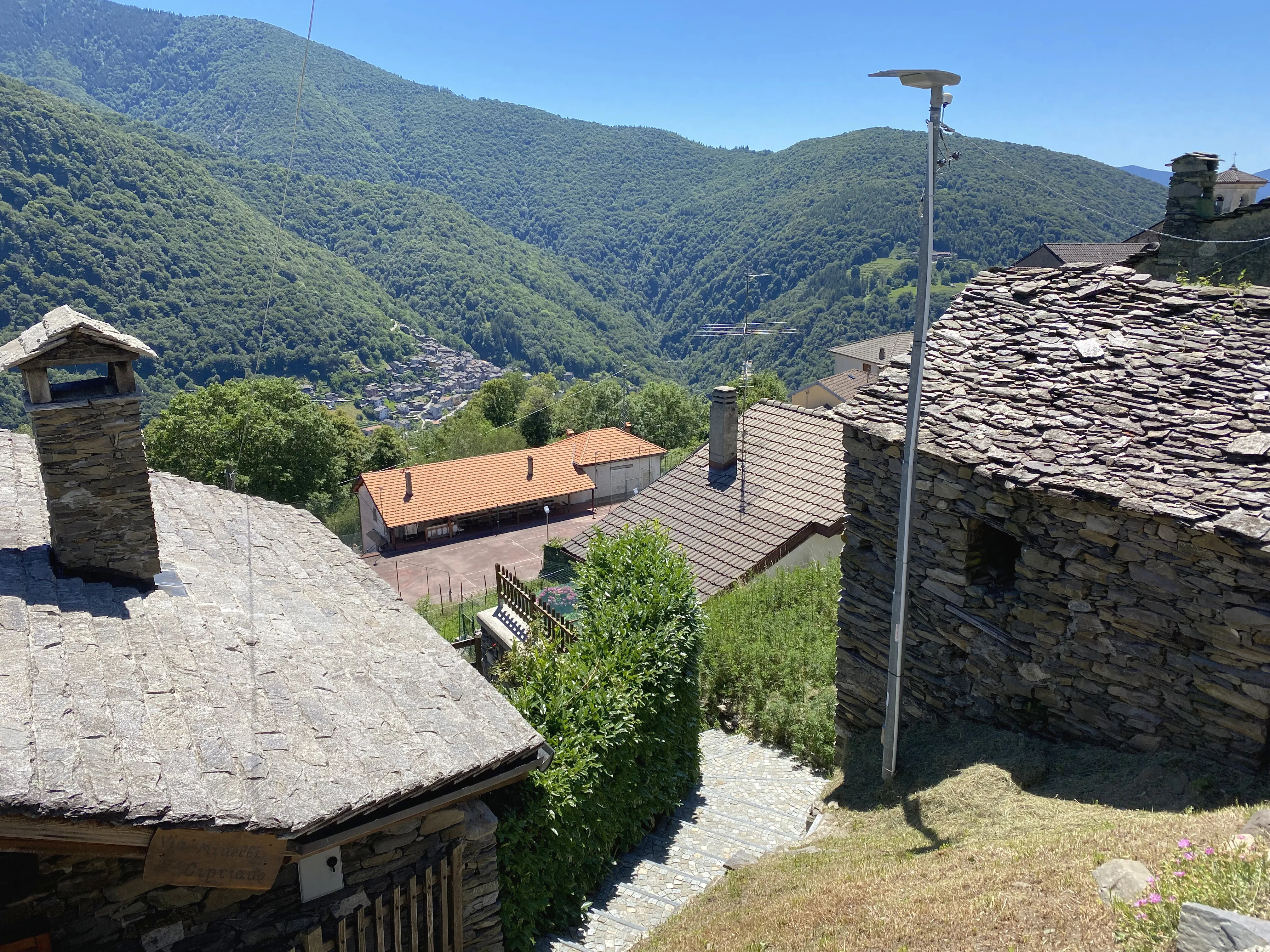 Slate roofs of a village in Ticino, the valley behind them.