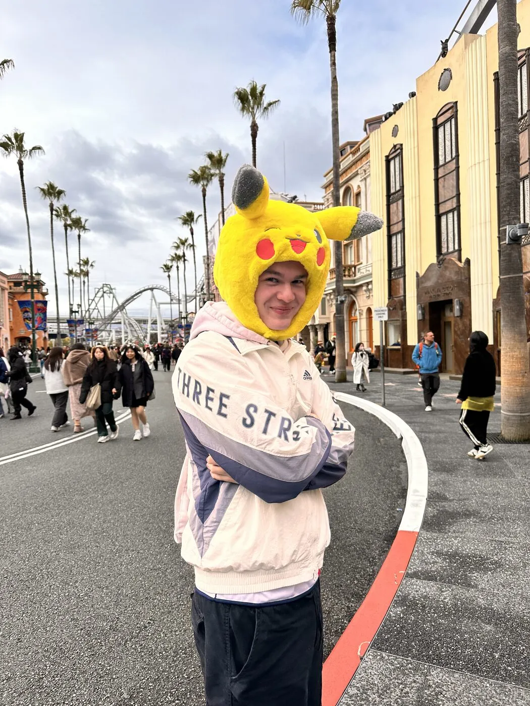 Wearing a Pikachu hood on a street lined with palm trees.